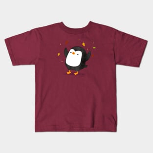 Penguin having fun with autumn leaves Kids T-Shirt